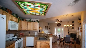 A kitchen with wooden cabinets, a white refrigerator, a microwave, and a stove. There is a dining area with a table and chairs. - Sedona Get-Away Sleeps  6 (Sedona)