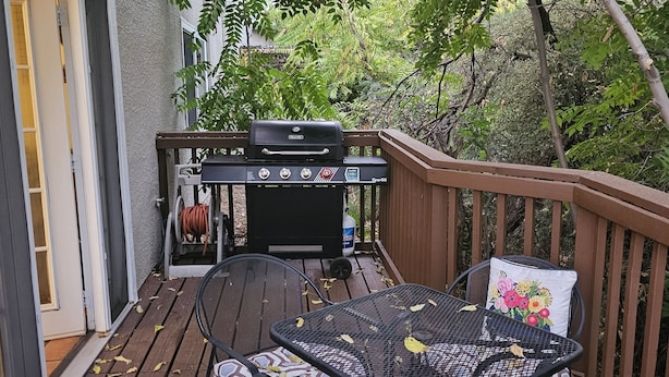 An outdoor deck with a grill, a table with chairs, and a view of trees and a building. - Sedona Get-Away Sleeps  6 (Sedona)