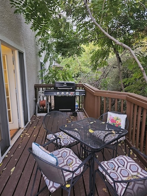 A wooden deck with a grill, outdoor table, and chairs.