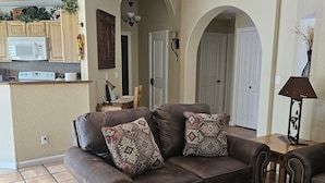 A living room with a brown leather sofa, patterned throw pillows, a wooden coffee table, and a kitchen area in the background. - Sedona Get-Away Sleeps  6 (Sedona)