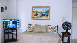 A bedroom with a bed, a TV, a painting, and a fan. - Inactive ad (capao da canoa)