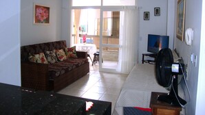 A living room with a sofa, a television, a fan, and a table. - Inactive ad (capao da canoa)