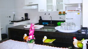 A kitchen with white cabinets, a black countertop, a sink, a coffee maker, and a refrigerator. - Inactive ad (capao da canoa)