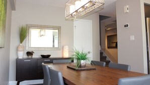 A modern dining area with a wooden table, grey chairs, a decorative plant centerpiece, and a pendant light fixture. - Chalet Style Townhome, Very Clean, Great Condition, Walk to Village, Mtn. Views. (The Blue Mountains)