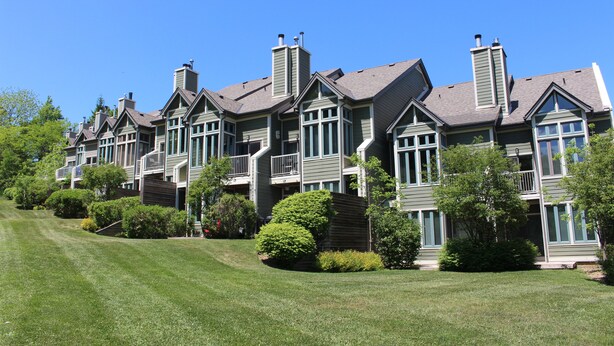 A row of townhouses with multiple chimneys, large windows, and a well-maintained lawn. - Chalet Style Townhome, Very Clean, Great Condition, Walk to Village, Mtn. Views. (The Blue Mountains)