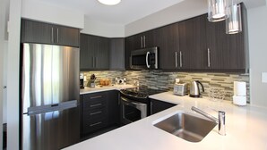 A modern kitchen with dark cabinets, stainless steel appliances, and a white countertop. - Chalet Style Townhome, Very Clean, Great Condition, Walk to Village, Mtn. Views. (The Blue Mountains)