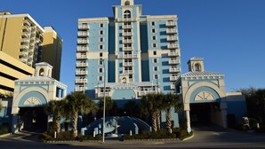 Un hotel de varios pisos con una torre central, balcones y una torre del reloj.