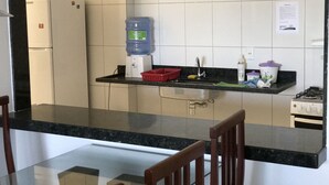 A kitchen with a refrigerator, a water dispenser, a sink, and a stove. - Apartment 702B with ocean view, Morro Beach, 3 bedrooms, 2 bathrooms, 1 garage. (Guarapari)