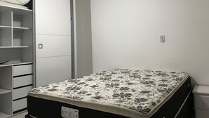 A bedroom with a bed, a wardrobe, and a small bedside table. - Apartment 702B with ocean view, Morro Beach, 3 bedrooms, 2 bathrooms, 1 garage. (Guarapari)