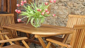 Une table en bois sur laquelle est posé un vase en verre rempli de tulipes roses, entourée de chaises en bois.