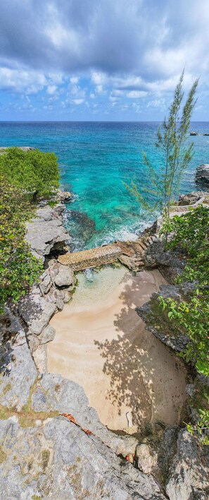 A coastal view with clear turquoise water, rocky shoreline, and greenery. - Archer's Rock-Luxurious Ocean front cottage at Chukka Cove w/Private Plunge Pool (Laughlands)