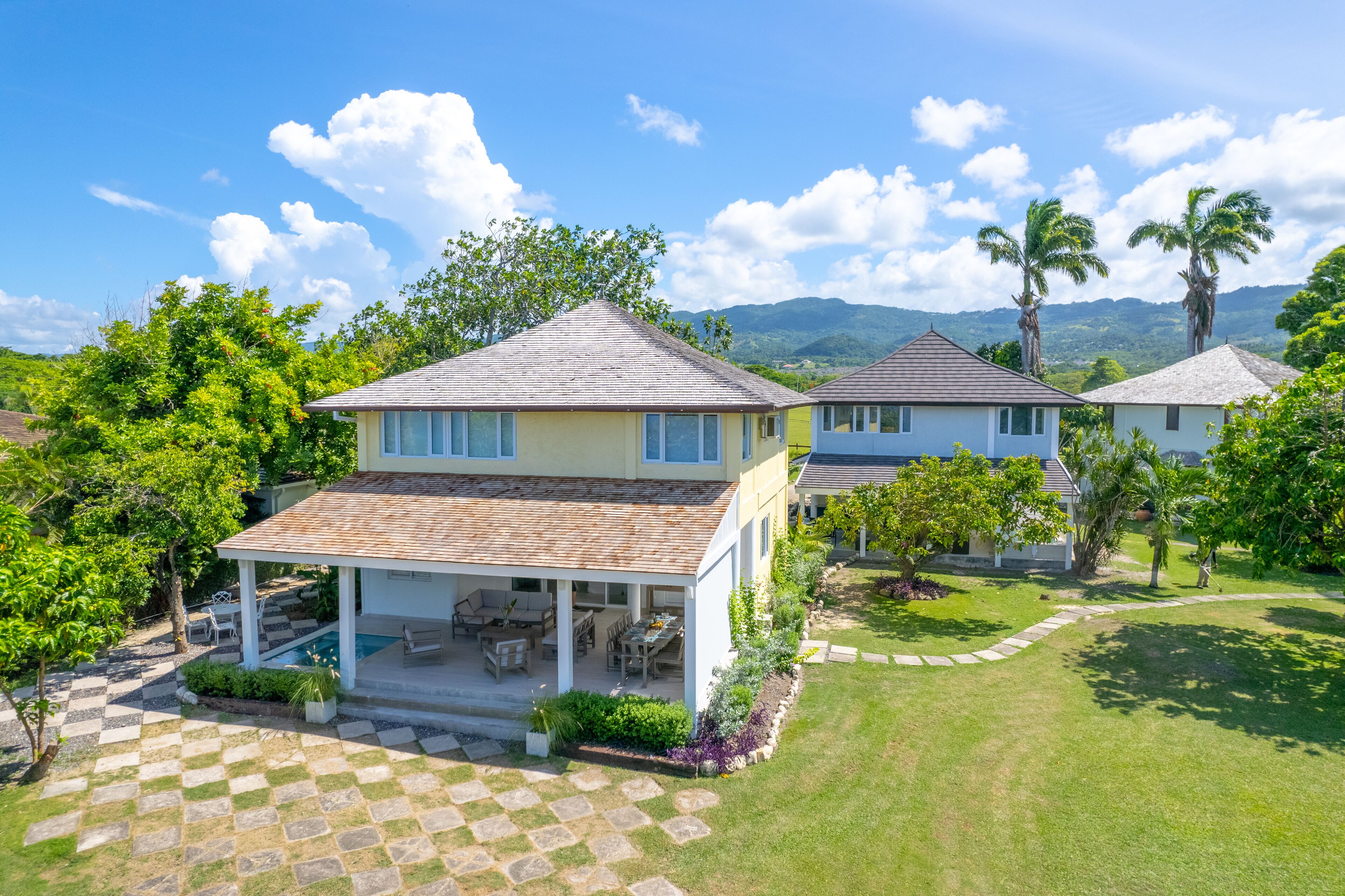 A two-story house with a covered patio and a swimming pool.