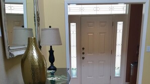 Un suelo de madera, un jarrón, una lámpara y una puerta con ventanal.