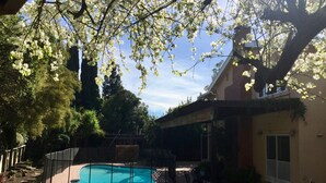 Un patio trasero con piscina, terraza techada y una casa.