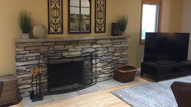 Una sala de estar con chimenea de piedra, un televisor de pantalla plana y decoración mural.