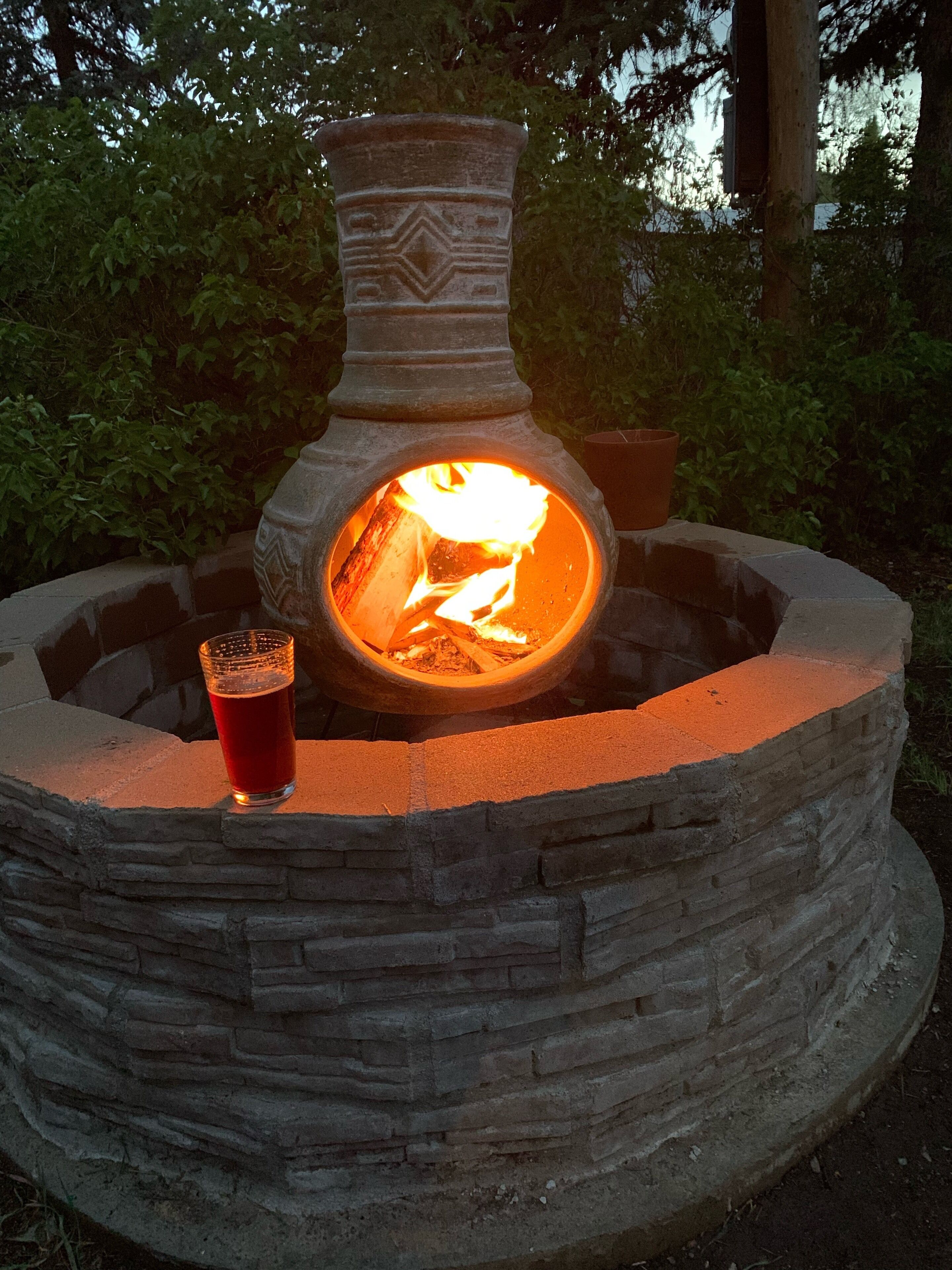 Une cheminée extérieure en pierre, avec un verre de bière posé sur une étagère en briques.