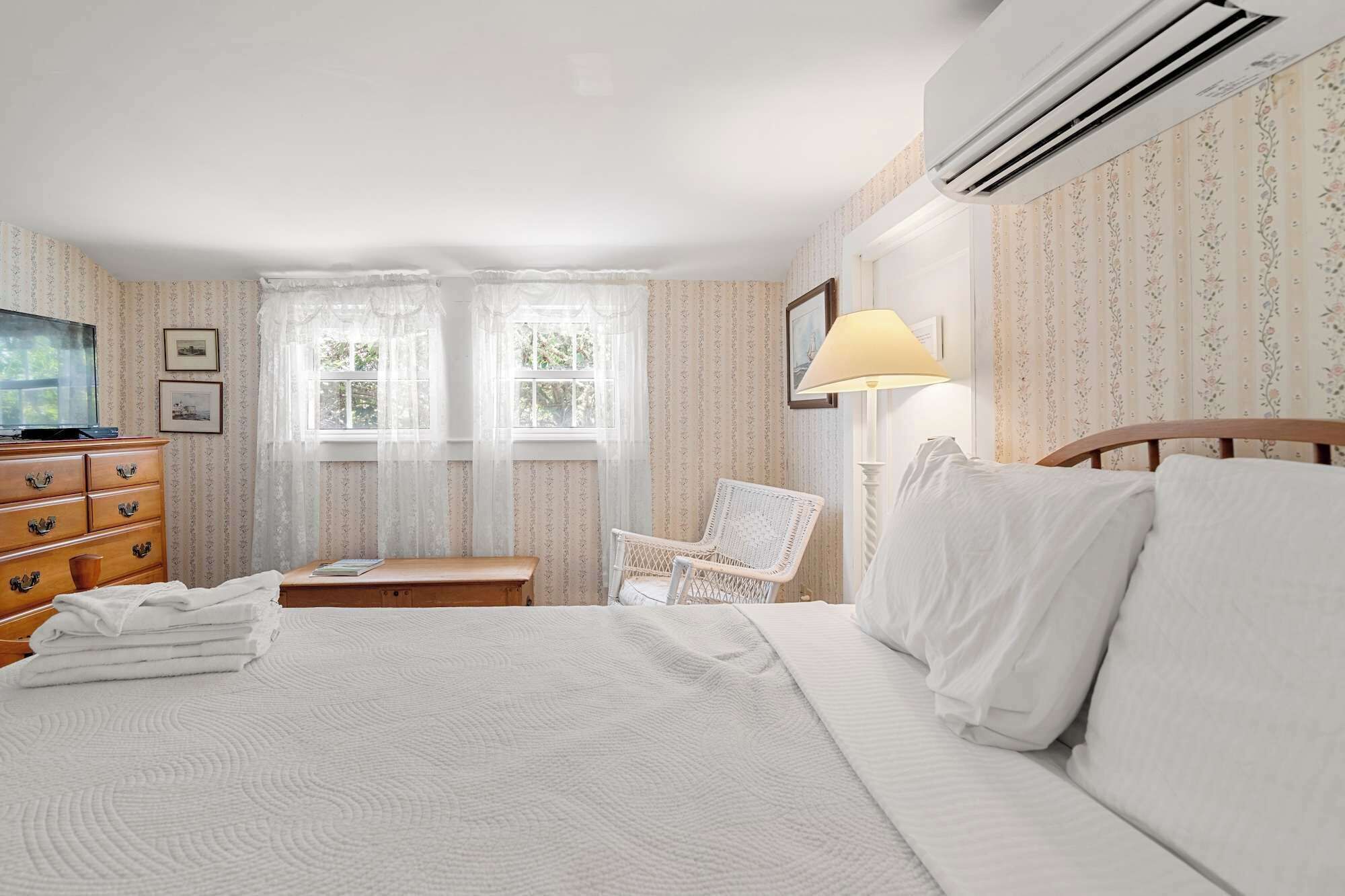 Une chambre d’hôtel comprenant un lit, une commode en bois, une chaise, un bureau et un téléviseur.