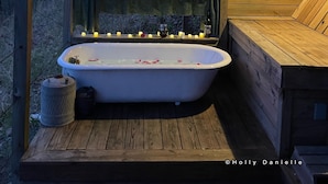 A wooden cabin with a freestanding bathtub, candles, and a sign that reads "Be fearless, bathe outside." - Secluded River Cabin Retreat with Outdoor Bathhouse and Kayaks on 80 acres! (Caddo Gap)