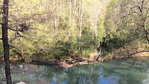 A wooden deck leading to a calm river with trees in the background. - Secluded River Cabin Retreat with Outdoor Bathhouse and Kayaks on 80 acres! (Caddo Gap)