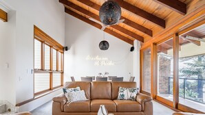 Uma sala de estar ampla com sofá de couro marrom, mesa de centro de madeira e ventilador de teto.
