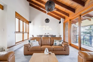 Een ruime woonkamer met een bruine leren bank, een houten salontafel en een plafondventilator.