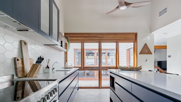 Cozinha moderna com uma ilha grande, eletrodomésticos de aço inoxidável e vista para o exterior.