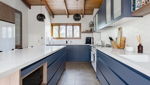 Uma cozinha moderna com uma ilha grande, eletrodomésticos embutidos e teto de madeira.