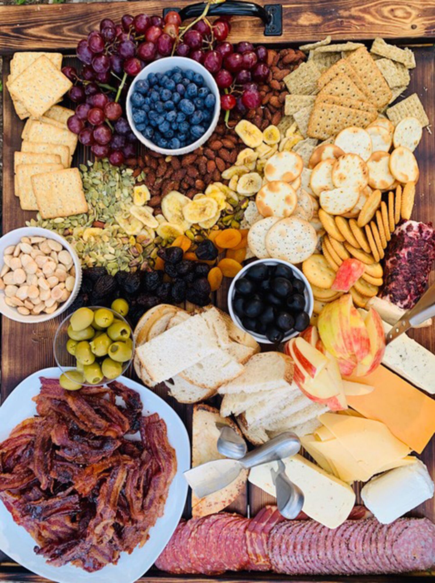 Een charcuterieplank met verschillende kazen, vleessoorten, fruit en noten.