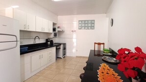 Een moderne keuken met witte kastjes, een zwart aanrecht en een eettafel met een rood bloemstuk.