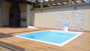 Een zwembad met een stenen muur en een pergola.