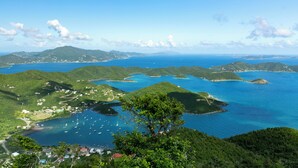 A coastal landscape with multiple islands, clear blue waters, and a view of boats anchored near the shore.