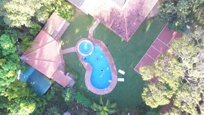 An aerial view of a backyard with a swimming pool, a tennis court, and a covered patio area. - Panama Santa Clara Beach Residence (Cocle)