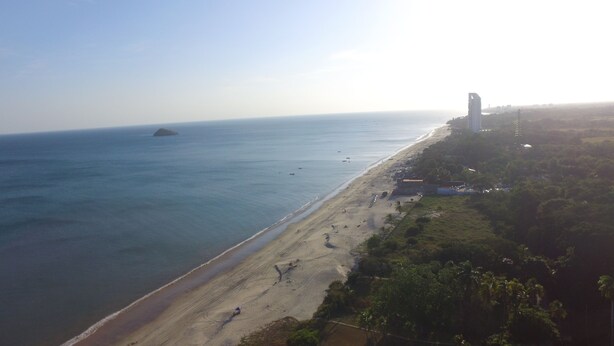 An aerial view of a beach with a clear sky, a sandy shore, and a few boats in the water. - Panama Santa Clara Beach Residence (Cocle)