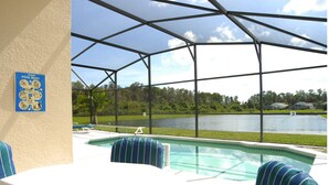 Un espace piscine doté d’une terrasse couverte, d’une table de billard et offrant une vue sur un lac.