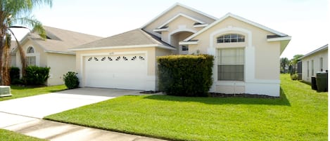 A single-story house with a garage, a well-maintained lawn, and a clear sky.