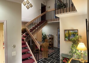 A staircase with wooden railings and red carpeted steps leading to a second floor.