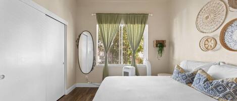 Une chambre à coucher avec un grand lit, une armoire, une fenêtre avec des rideaux et des éléments décoratifs sur les murs.