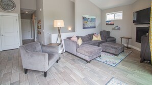 A living room with grey sofas, a lamp, a flat-screen TV, and a fireplace.