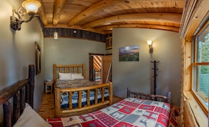 Une pièce chaleureuse avec un lit en bois, une fenêtre donnant sur un beau paysage et un plafond en bois.