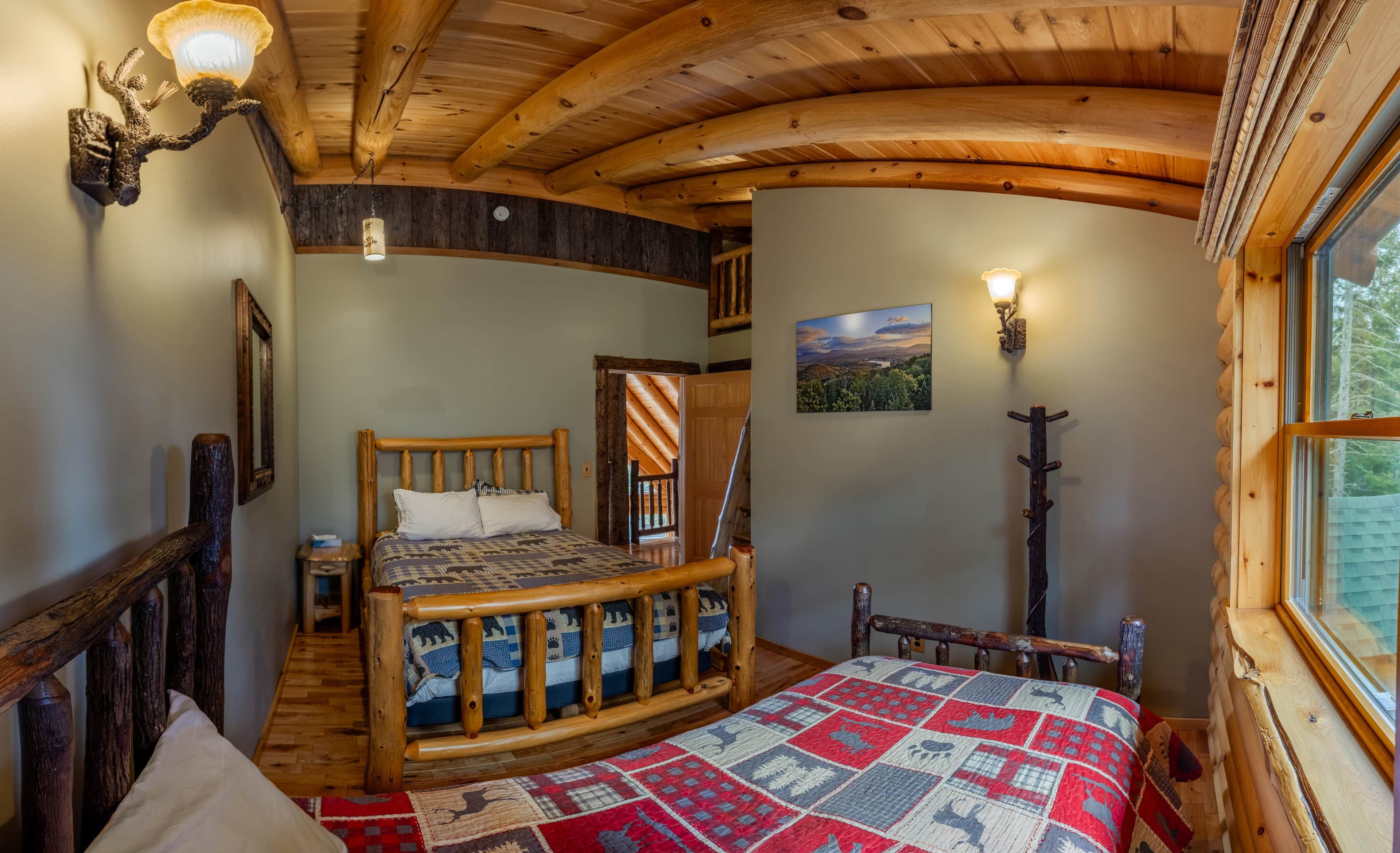 Ein gemütliches Zimmer mit einem hölzernen Bett, einem Fenster mit Blick und einer Holzzieldecke.