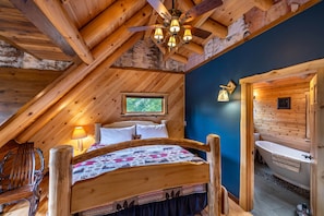 Une chambre confortable située dans les combles, avec un lit en bois, un bureau et une vue sur l’extérieur.