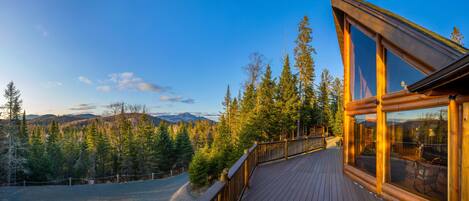 A wooden deck with a view of a forest and mountains.