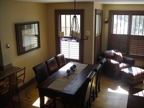 Uma sala de jantar com mesa de madeira, cadeiras de couro e um lustre.