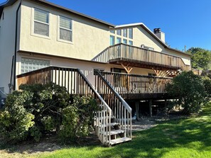 Une maison à deux étages dotée d’une terrasse en bois et d’un escalier menant à l’étage supérieur.
