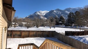 Una terraza de madera cubierta de nieve, una cerca de madera y una montaña al fondo.