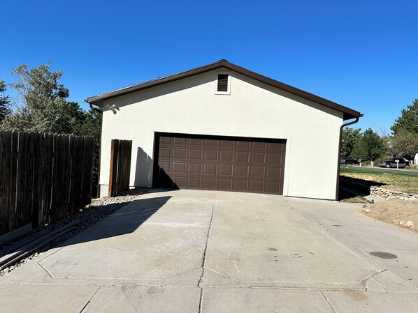 A single-story building with a garage, a sloped roof, and a concrete driveway.