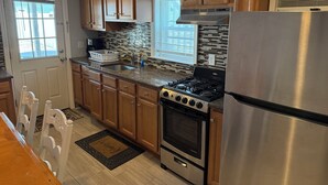 A kitchen with wooden cabinets, a stainless steel refrigerator, a gas stove, and a window with blinds.