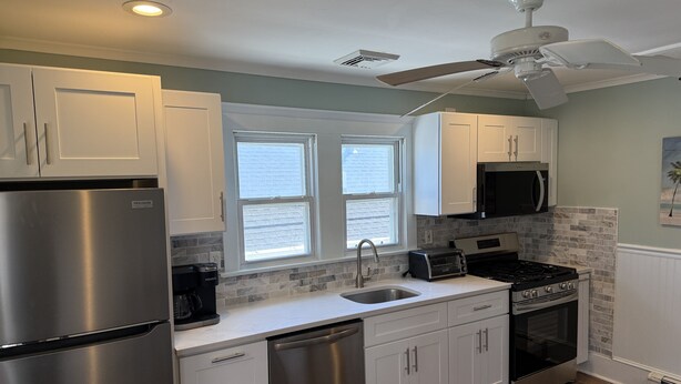 A modern kitchen with white cabinets, stainless steel appliances, a dishwasher, a toaster, and a stove.
