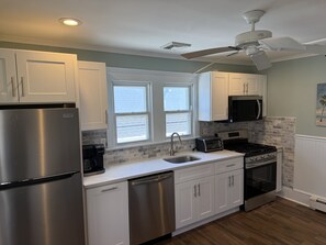 Una cocina moderna con armarios blancos, electrodomésticos de acero inoxidable, lavavajillas, tostadora y estufa.