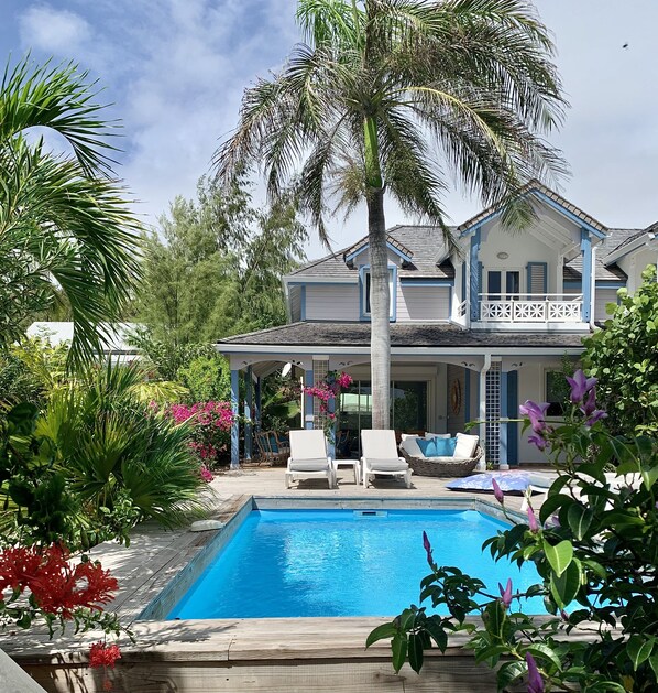 A house with a pool, surrounded by tropical plants and a palm tree. - 2 bedrooms, private pool and sea view (Orient Bay)